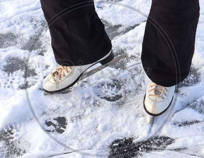 Close Up On Womans Feet Wearing Ice Skating Boots And Standing On Ice.