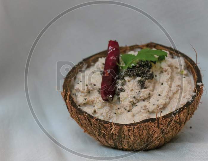 the coconut chutney served in a coconut shell with white background