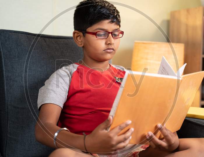 Young Kid Busy Reading From Book For Exam At Home - Concept Of Education And Teenager Kids Lifestyle.