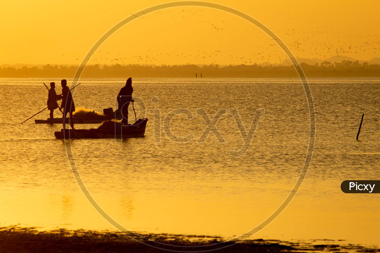 Silhouette View Of The Fishermen With Their Boats In A Lake During Sunset. Selective Focus