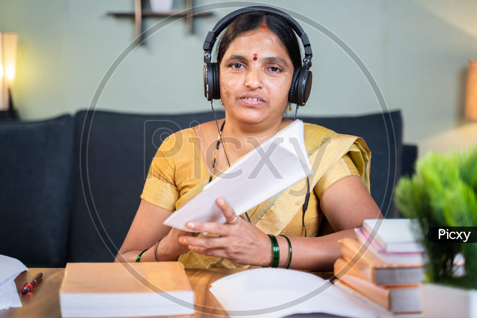 Indian Woman Busy Explaining From Book During Online Class By Looking Camera At Home - Concept Of E-Teaching, Remote Learning, Virtual Education During Coronavirus Pandemic