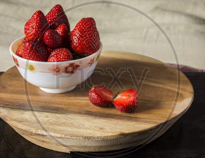 Fresh Organic Red Strawberry Cut Into Two Pieces And Some In A Bowl On Wooden Table.
