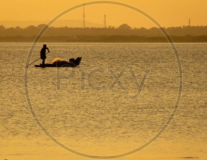 Silhouette View Of The Fisherman With His Boat In A Lake During Sunset. Selective Focus