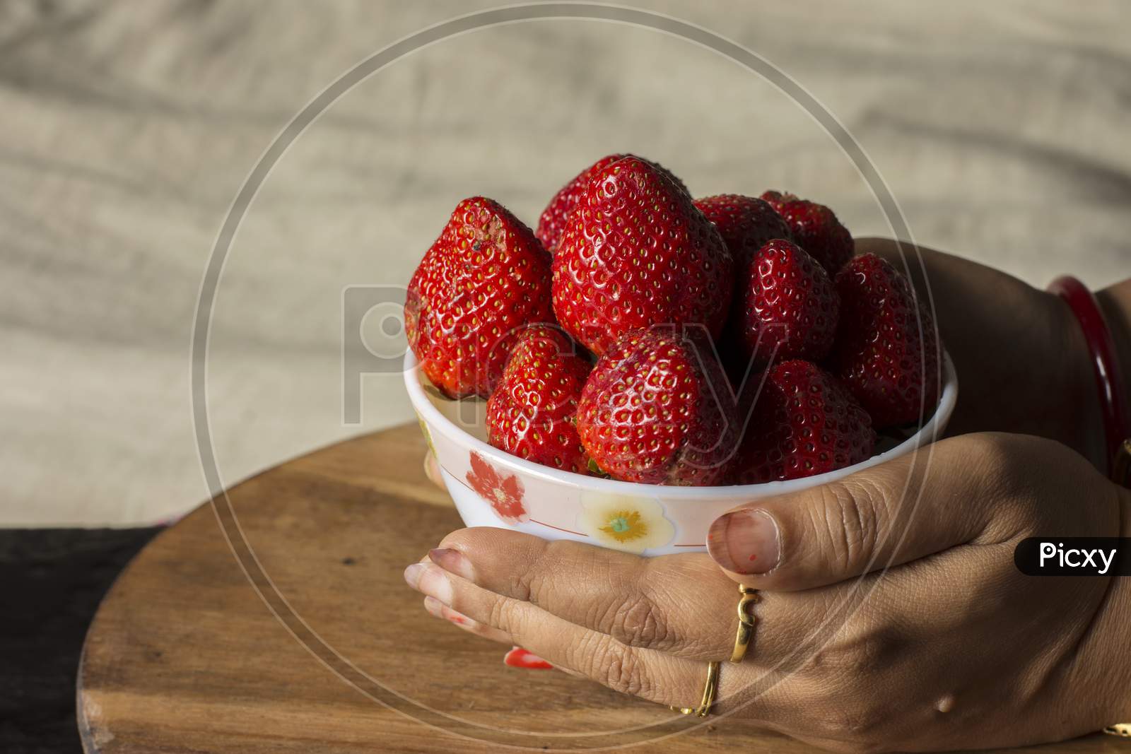 A Female Hand Holding Fresh Organic Red Strawberry In A Bowl On Wooden Table.