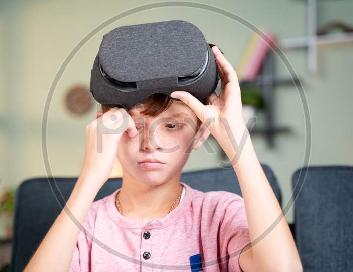 Concept Showing Of Over Use Of Vr Or Virtual Reality Console - Young Kid Rubbing His Eyes After Using Of Vr Headset