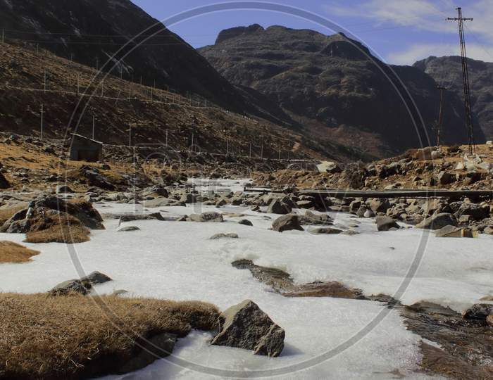 alpine tundra landscape and valley with frozen stream, near sela pass in tawang distric of arunachal pradesh, north east india