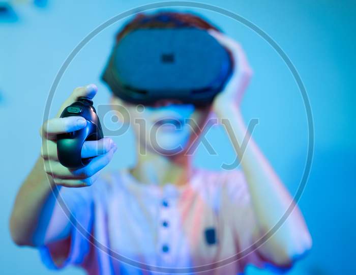 Selective Focus On Joystick, Young Kid Playing Video Game By Wearing Vr Or Virtual Reality Headset Using Game Pad Or Joystick.