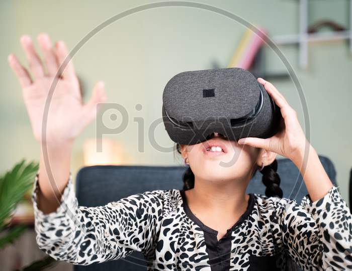 Young Girl Kid With Vr Or Virtual Reality Goggles Feeling Or Enjoying The 360 Degree Virtual Environment At Home - Concept Of Showing Modren Vr Technology In Modern Lifestyle.