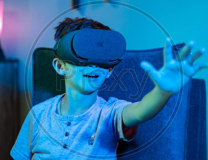 Young Kid With Vr Or Virtual Reality Headset Feeling Or Enjoying The 360 Degree Virtual Environment - Concept Of Showing Futuristic Of Modern Vr Technology In Modern Lifestyle.