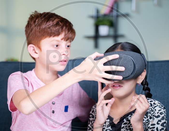 Young Kid Helping His Sister To Wear Vr Or Virtual Reality Headset At Home - Concept Of Togetherness, Bonding And Use Of Technology.