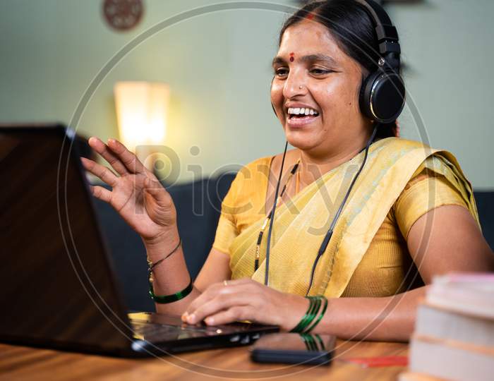 Happy Indian Woman With Headphones Busy Talking In Video Call On Laptop - Concept Of Online Chat, Distance Webinar, Video Conference During Work From Home