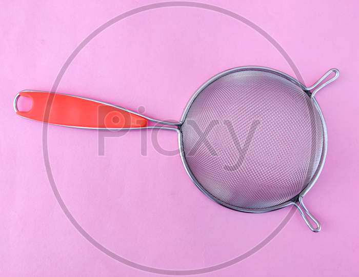 Top View Of Stainless Steel Soup & Juice Strainer Or Liquid Filter With Handle Isolated On Pink Background