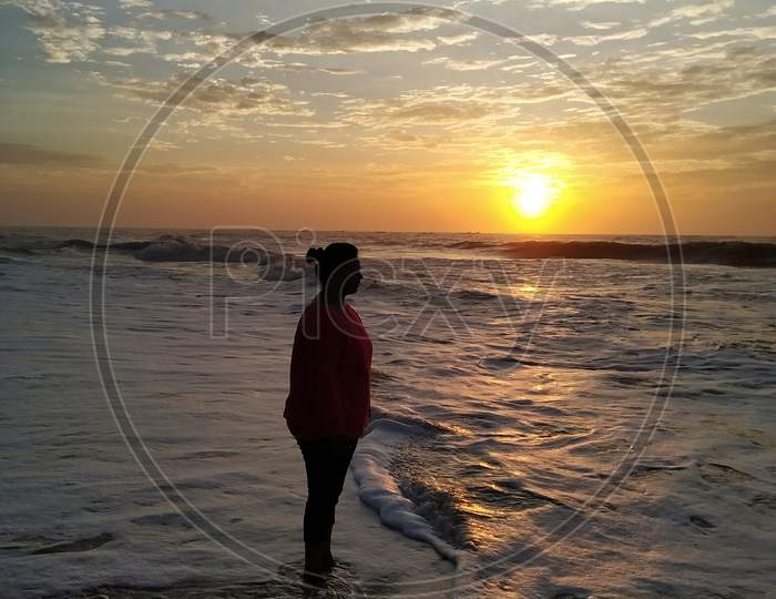 Young woman enjoying the waves in the sea and sunrise, Mahabalipuram Beach