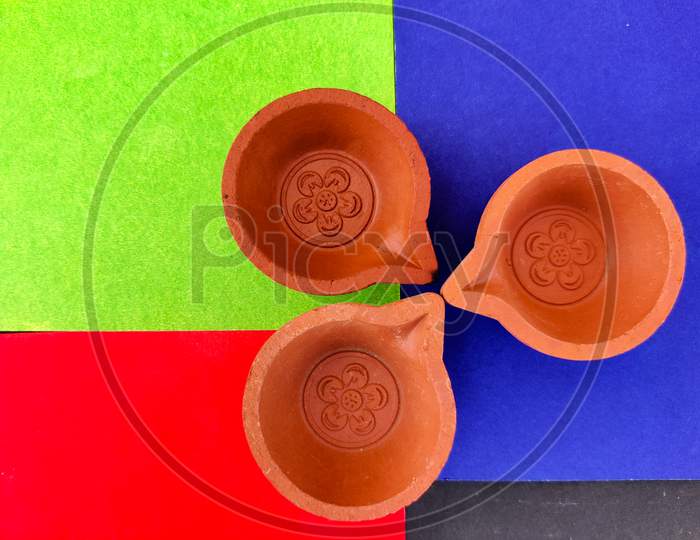 Top View Of Three Clay Lamps Or Diya Or Oil Lamps Isolated On Red And Blue And Green Background