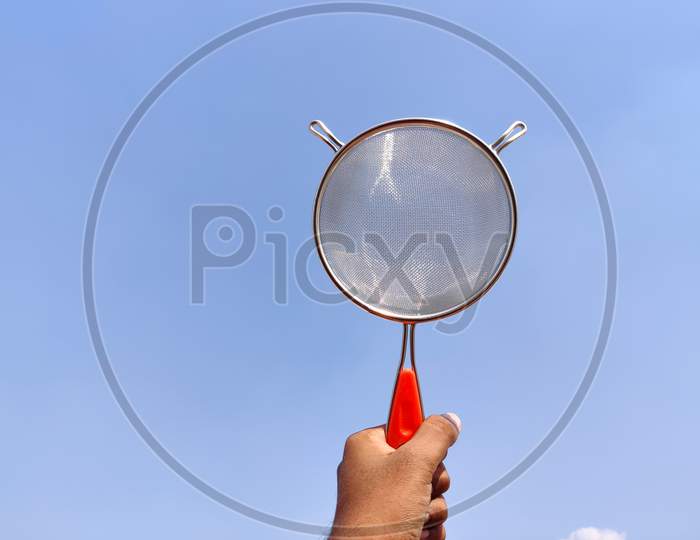 South Indian Man Holding Stainless Strainer Or Liquid Filter. Cloud Background