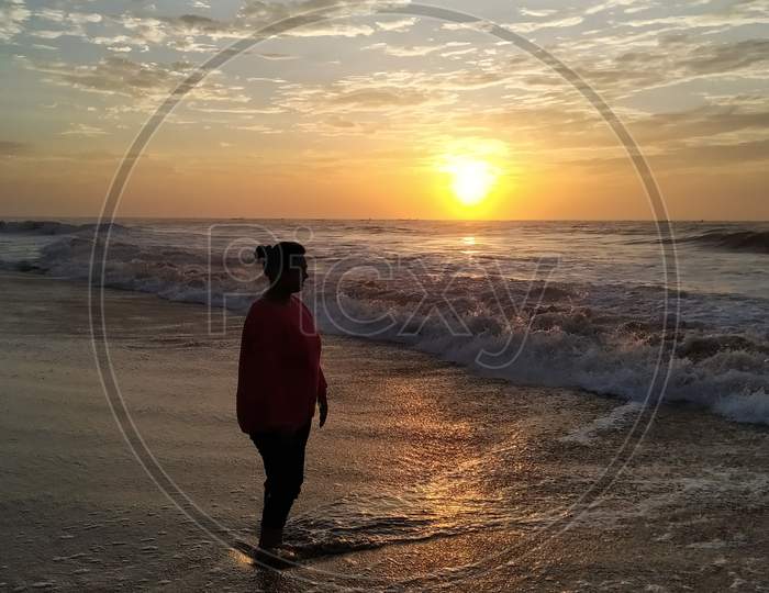 Young woman enjoying the waves in the sea and sunrise, Mahabalipuram Beach