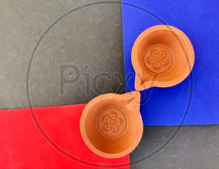 Top View Of Two Clay Lamps Or Diya Or Oil Lamps Isolated On Red And Blue Background