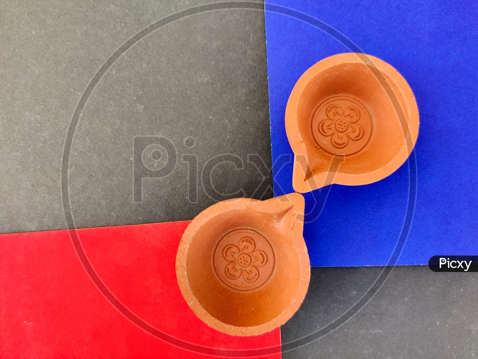 Top View Of Two Clay Lamps Or Diya Or Oil Lamps Isolated On Red And Blue Background