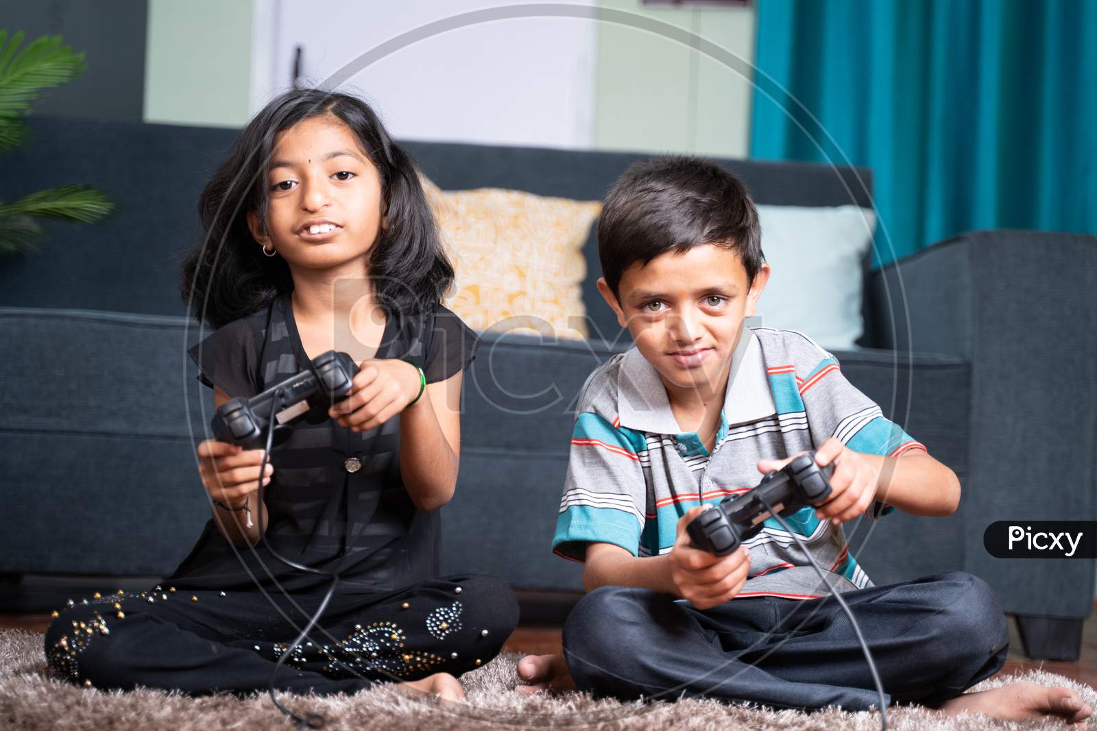 Two Kids Busy Playing Video Game Using Joystick At Home While Sitting On Floor - Concept Of Kids Game Addiction And Leisure And Weekend Activity And Lifestyle.