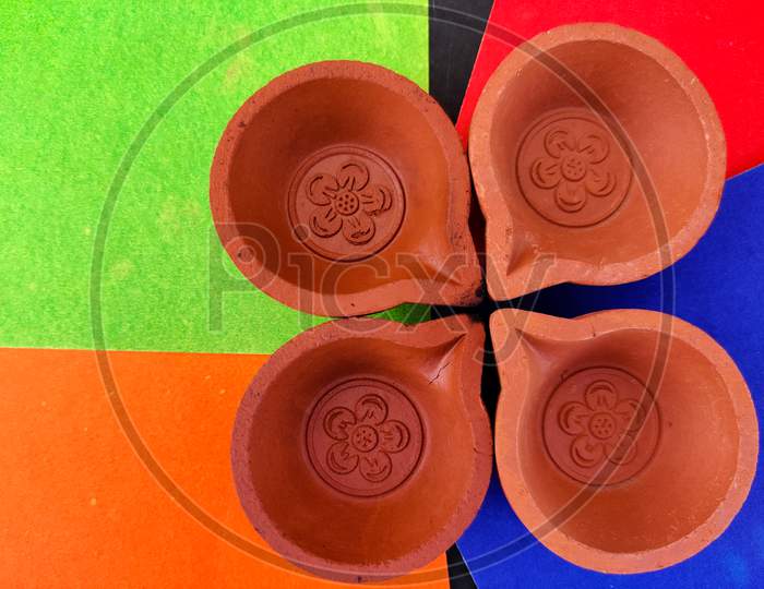Top View Of Four Clay Lamps Or Diya Or Oil Lamps Isolated On Red And Blue And Green, Orange Background