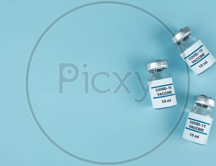 Medicine Bottles With Covid 19 Vaccine On Blue Background With Copy Space.
