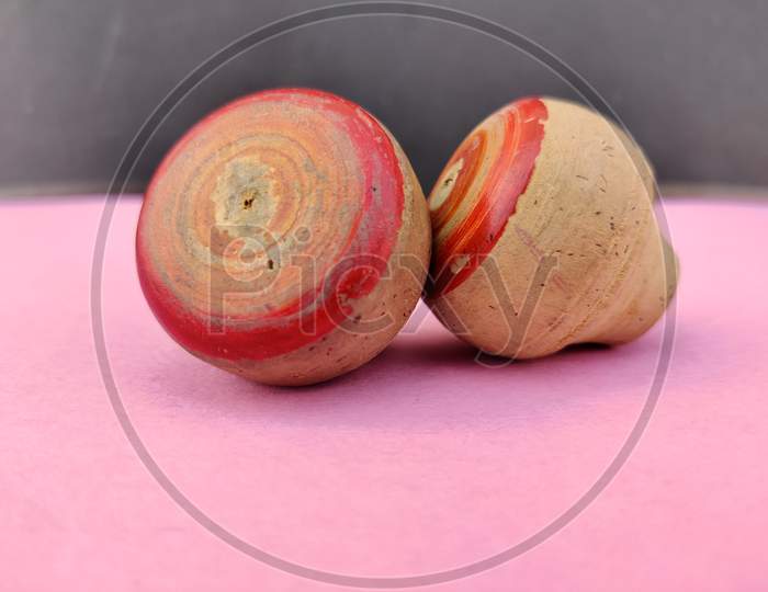 Side View Of Two Small Wooden Spinning Top Toys Isolated On Pink Background