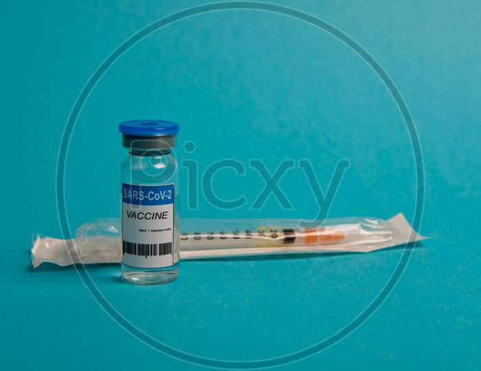 Covid-19 Coronavirus Vaccine Bottle And Syringe On Blue Background. Selective Focus.
