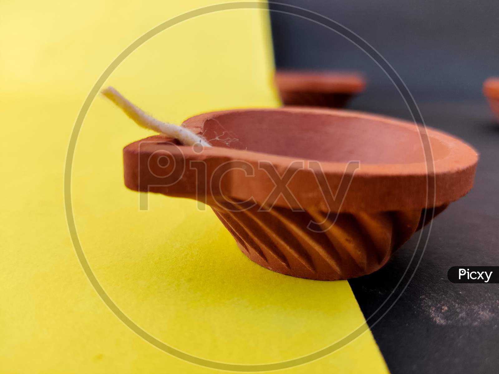 A Pattern Clay Lamp With Wick Isolated On Yellow And Black Background.