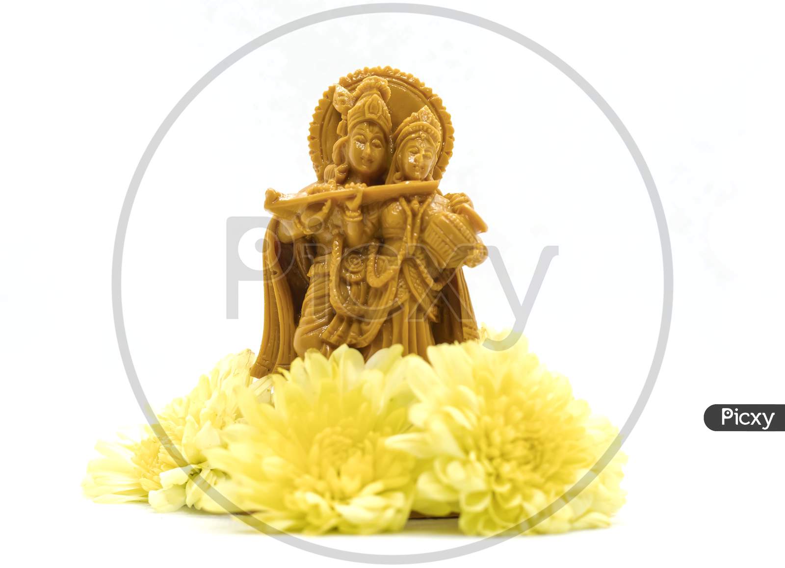 The Statue Of Radha Krishna With Flowers Is Isolated On A White Background