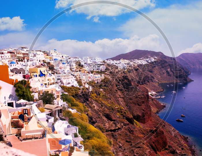 Santorini, Greece - September 11, 2017: Wide Angle Shot Of Santorini Cityscape In The Town Of Oia Against Dramatic Clouds. Small White Houses On Cliff In Famous Greek Island