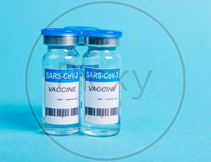 Covid-19 Coronavirus Vaccine Bottle On Blue Background.