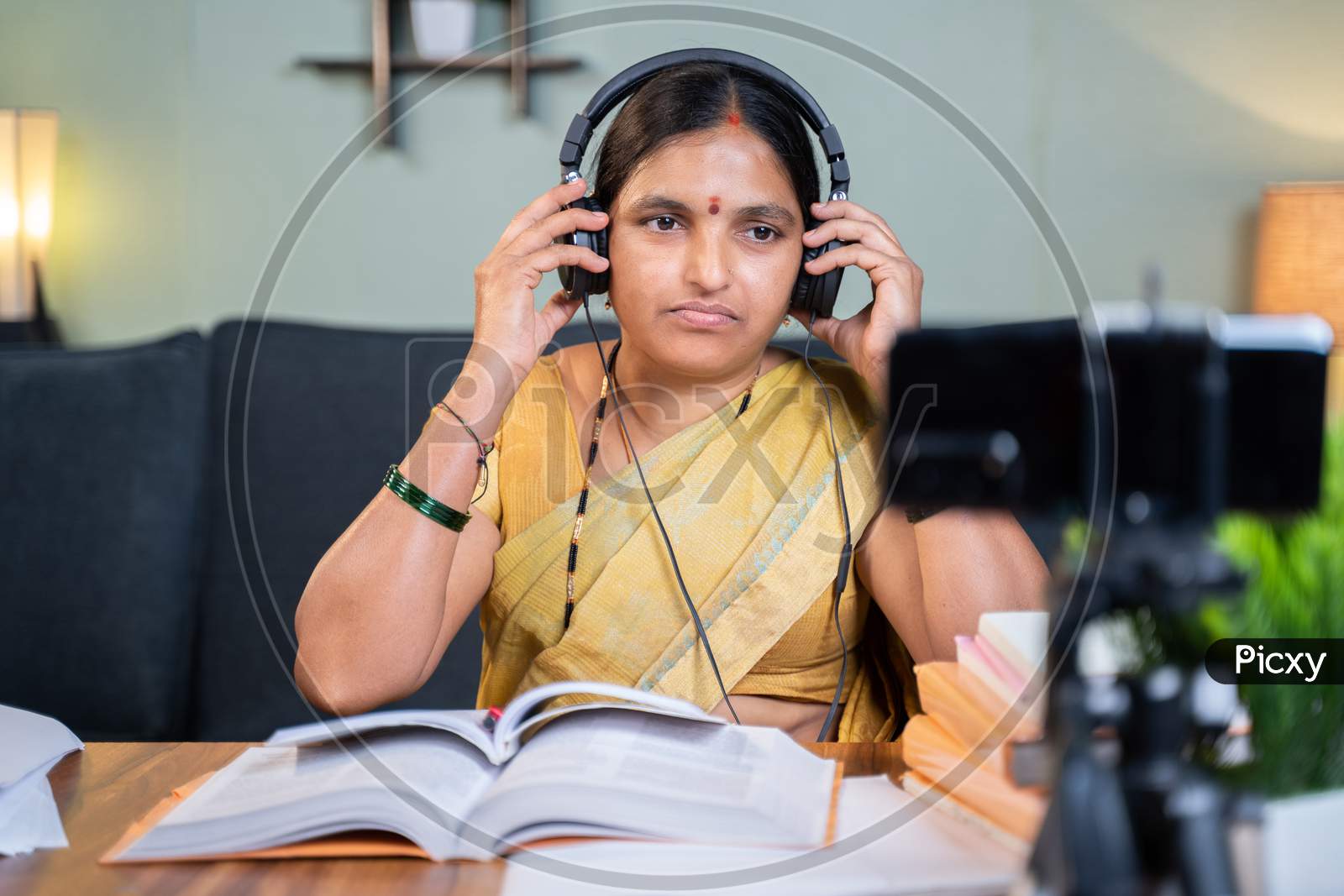 Indian Woman Preparing For Online Class By Wearing Headphone In Front Of Mobile Phone At Home - Concept Of Virtual Education And New Normal Lifestyle.