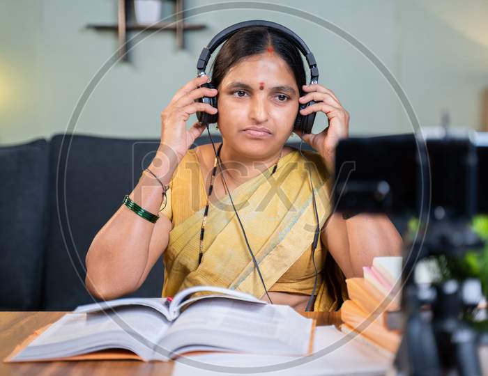Indian Woman Preparing For Online Class By Wearing Headphone In Front Of Mobile Phone At Home - Concept Of Virtual Education And New Normal Lifestyle.