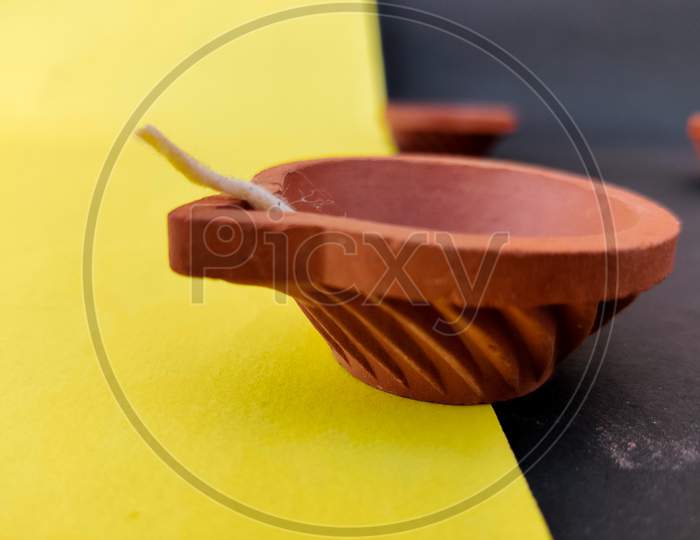 A Pattern Clay Lamp With Wick Isolated On Yellow And Black Background.