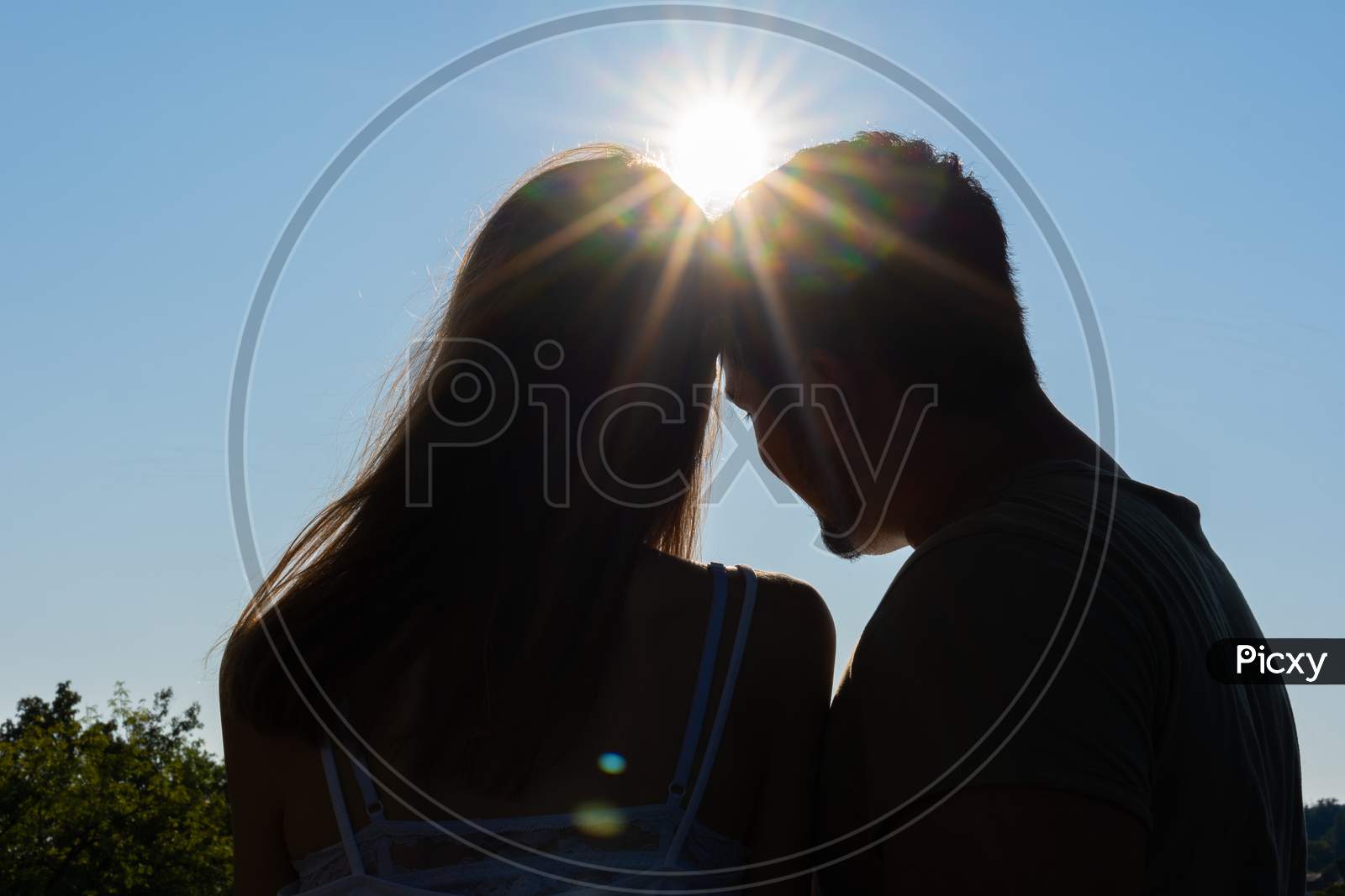 Silhouette Of dreaming Couple Against Deep Blue Sky With Sunbeams. Low Angle View, Concept.
