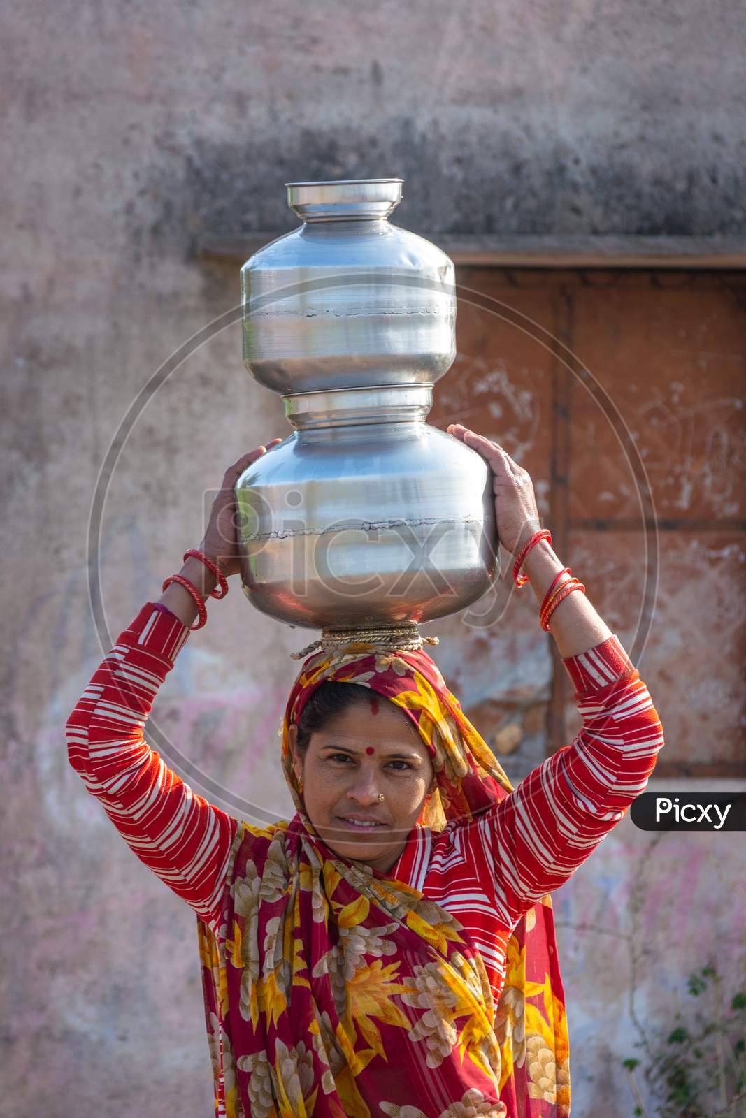TIKAMGARH, MADHYA PRADESH, INDIA - JANUARY 23, 2021: An Indian woman carrying a container of water on her head.