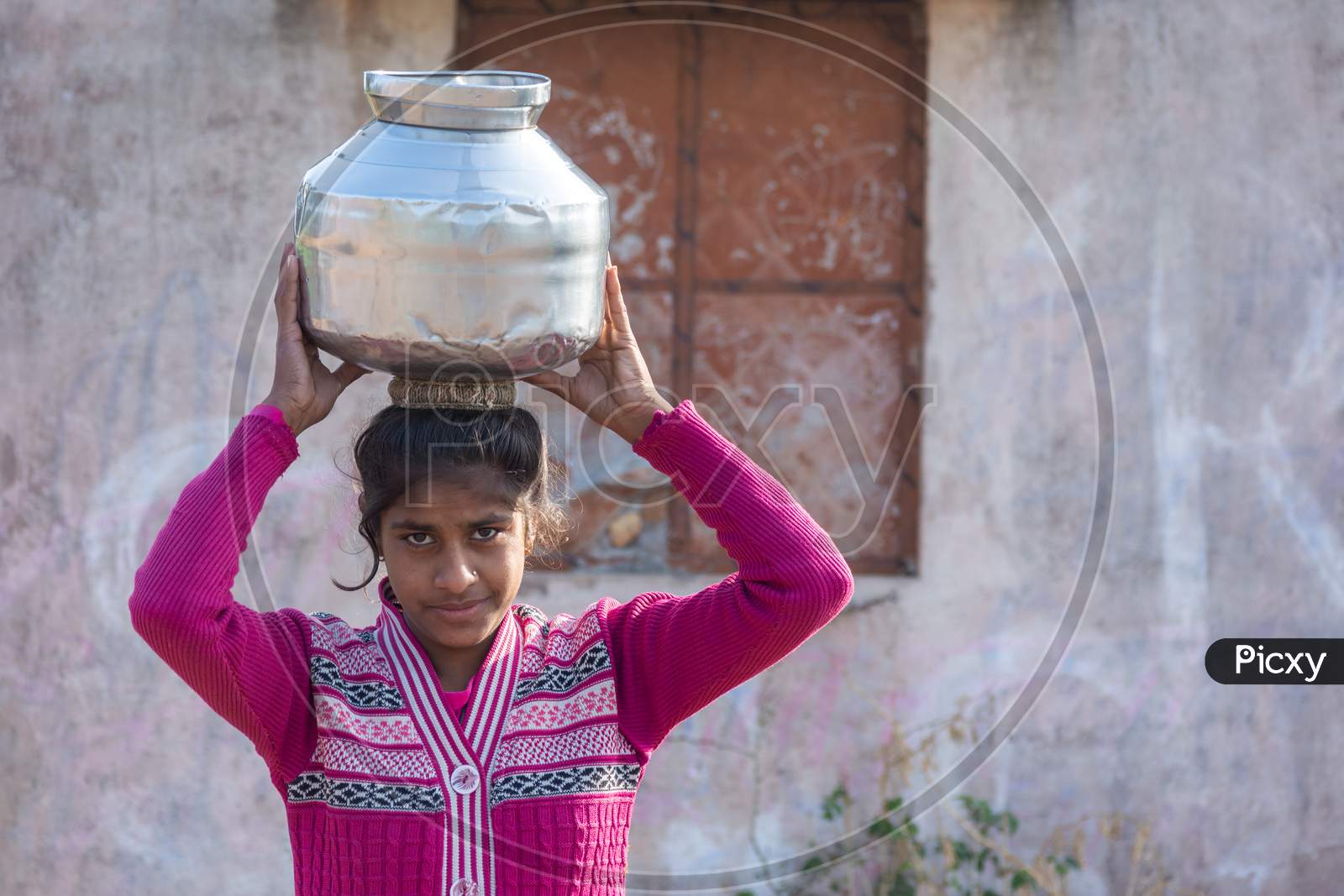 TIKAMGARH, MADHYA PRADESH, INDIA - JANUARY 23, 2021: An unidentified indian village girl carry water on their heads in traditional pots from well, An Indian rural scene.