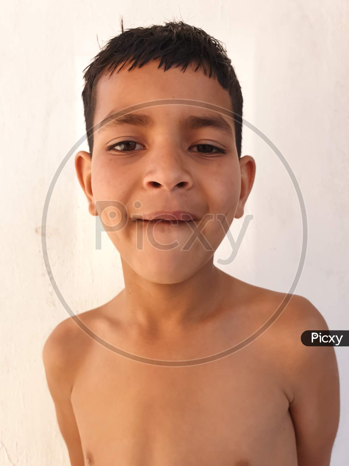 Closeup of a shirtless small boy with funny reaction, A south asian kid looking at camera