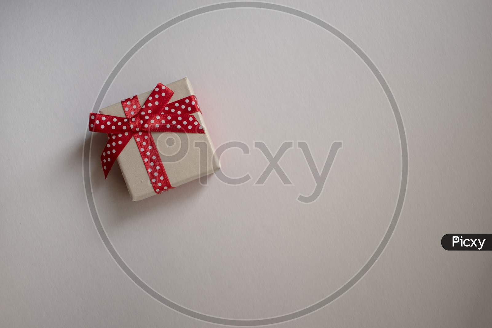 A Small Gift Box With Tied Decorative Bow And Red Ribbon