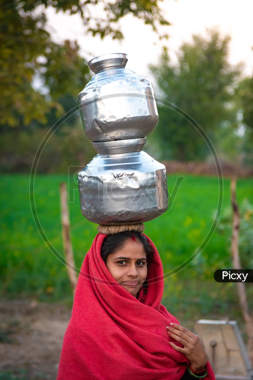 TIKAMGARH, MADHYA PRADESH, INDIA - JANUARY 23, 2021: An Indian woman carrying a container of water on her head.