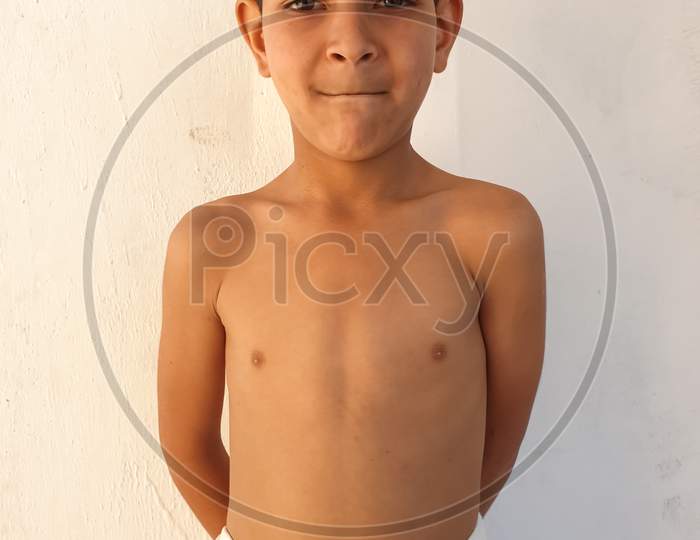 Portrait of a shirtless small boy with wearing white towel, A Indian kid looking at camera