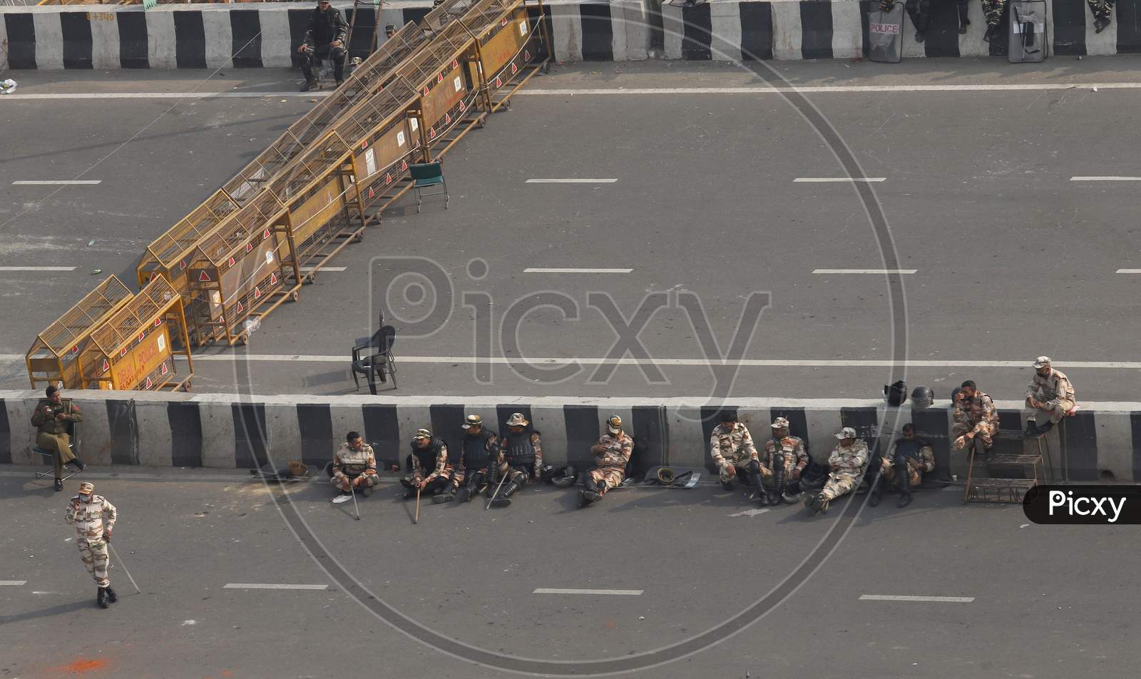 Policemen sit near the barricades as farmers continue their protest against the central government's recent agricultural reforms at Delhi-Uttar Pradesh border in Ghaziabad on February 2, 2021.