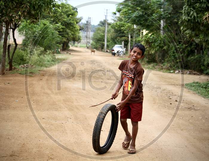 Village kid playing with a rubber tire.