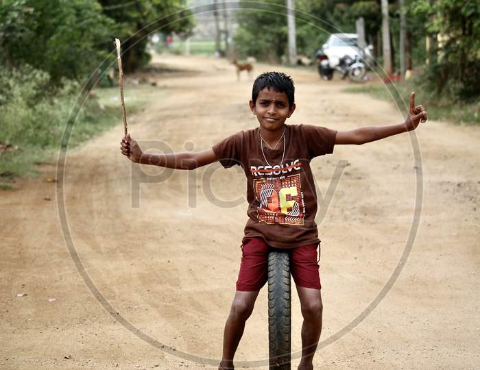 Village kid playing with a rubber tire.
