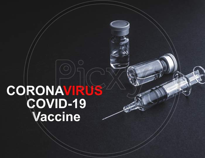 Coronavirus Covid-19 Vaccine Text With Syringe And Vials On Black Background