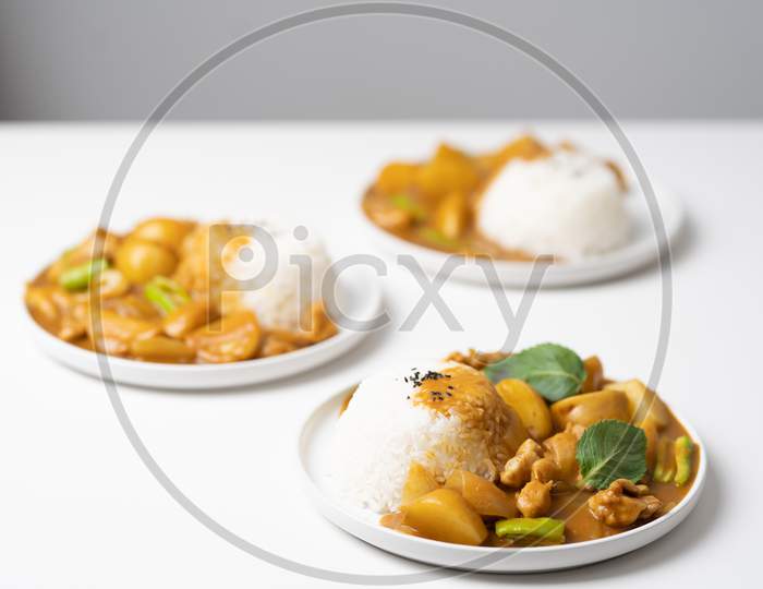 Plates with tasty Curry & rice placed on white table