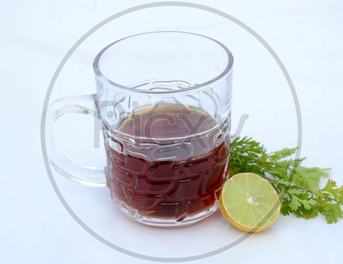 The Black Lemon Tea In The Glass Cup With Anise And Lemon On The White Background.