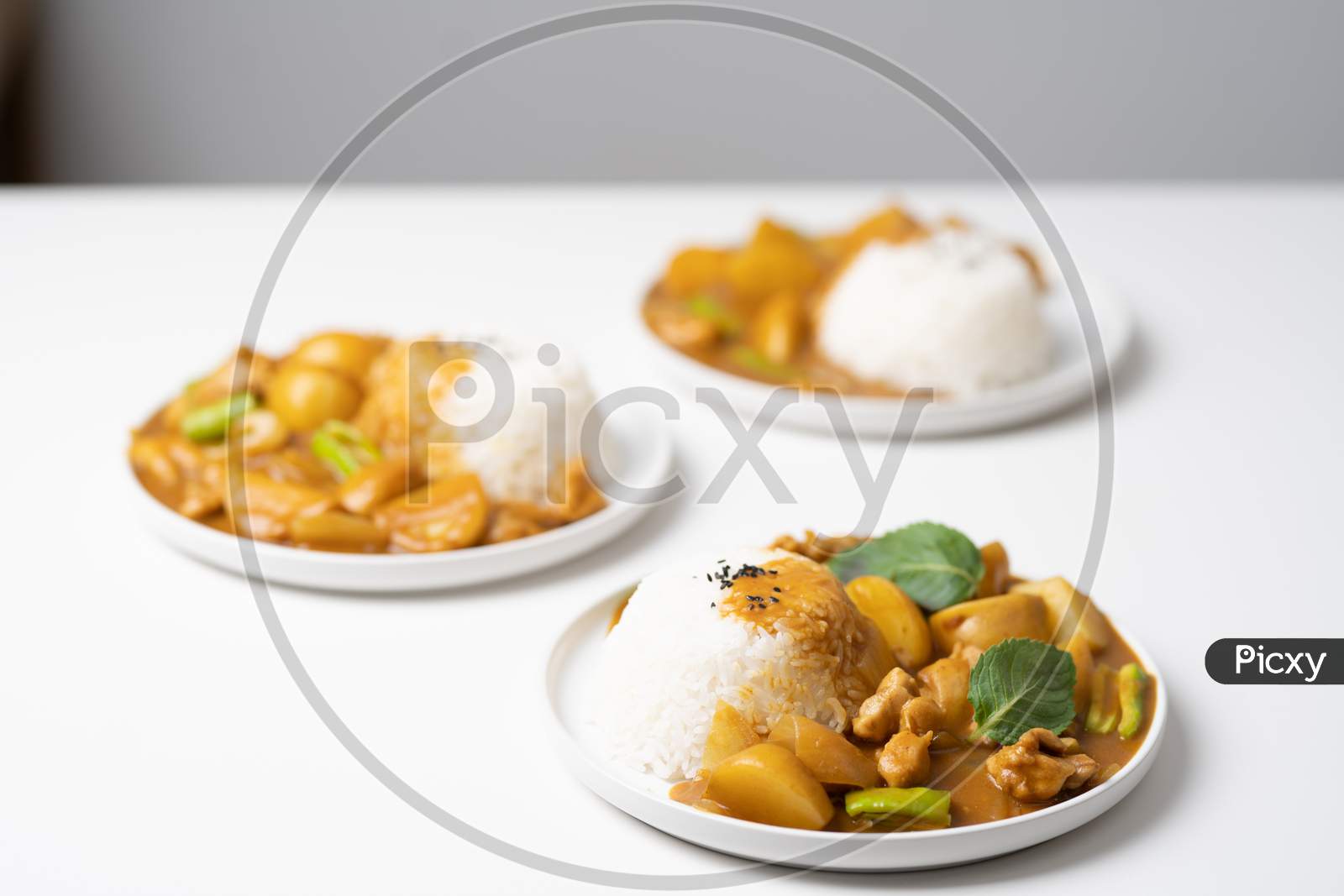 Plates with tasty Curry & rice placed on white table