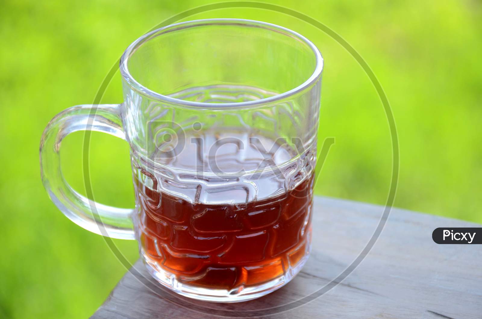 The Black Lemon Tea In The Glass Cup On The Wooden Brown And Green Background.