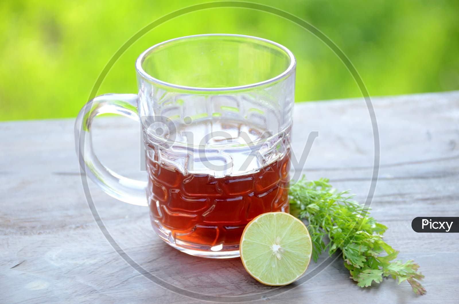 The Black Lemon Tea In The Glass Cup With Anise And Lemon On The Brown Green Background.